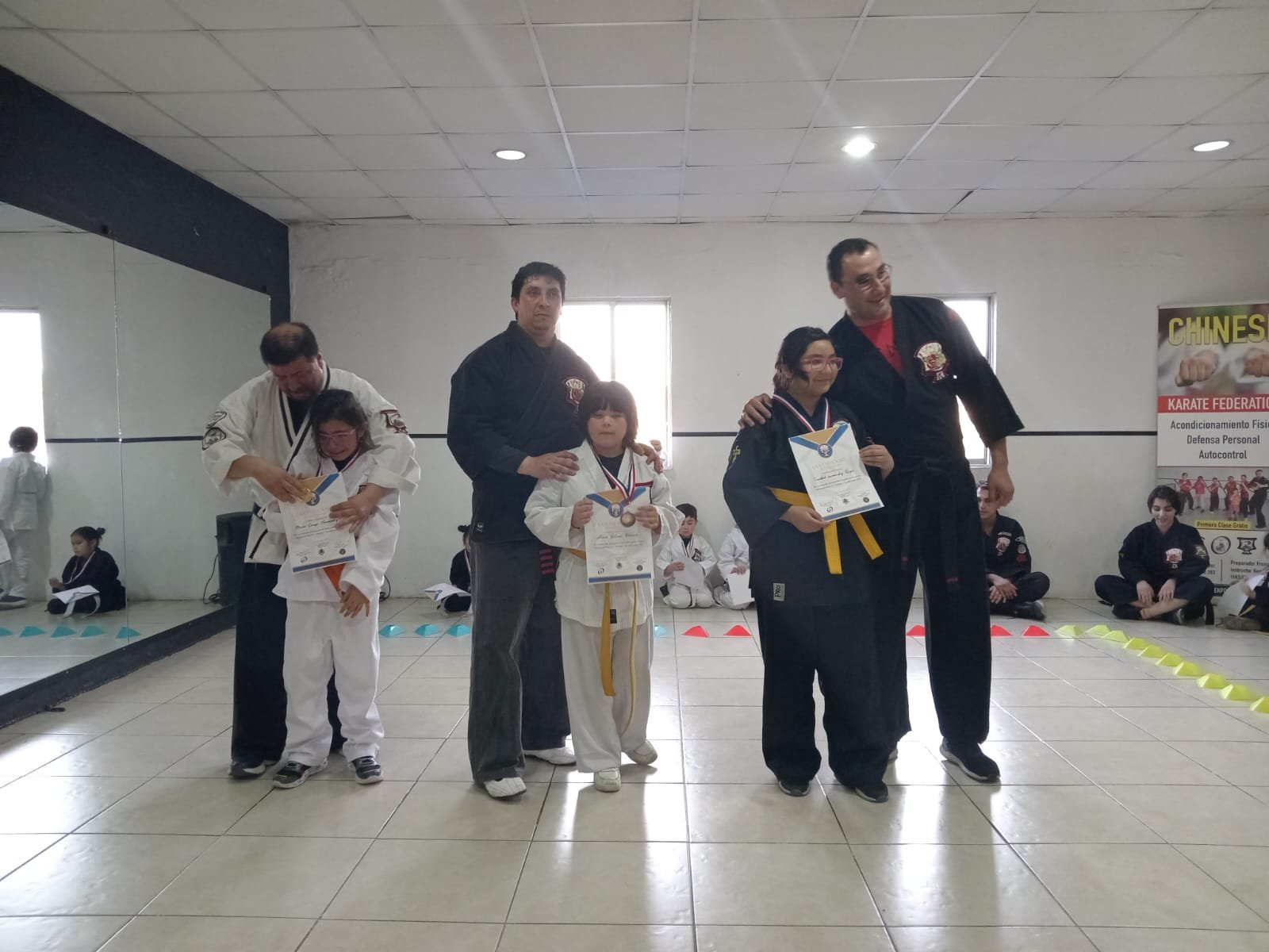 Entrega de certificados y cinturones a alumnos de la escuela tras un examen de grado